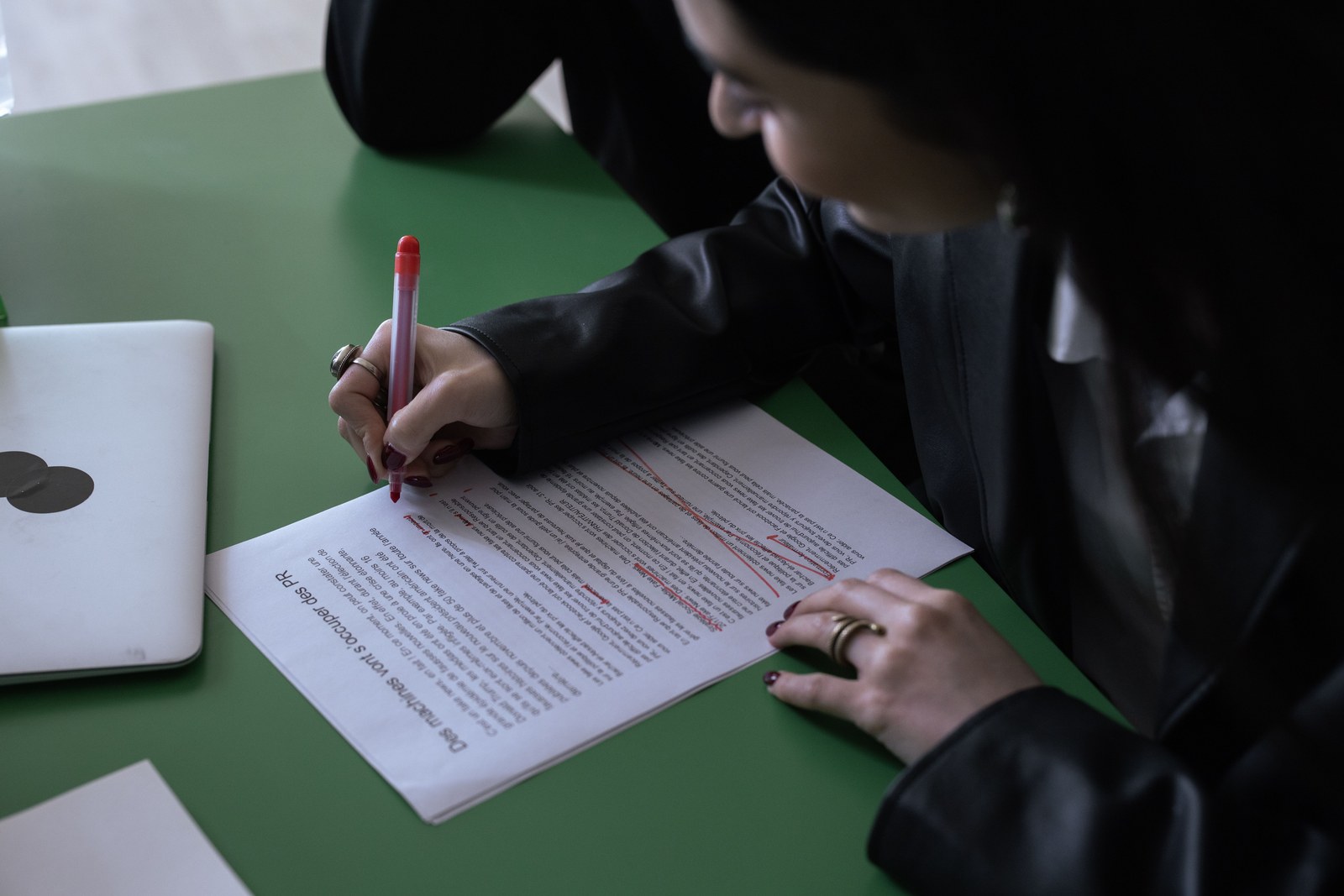 Someone marking specific sentences in a printed article with a red pen