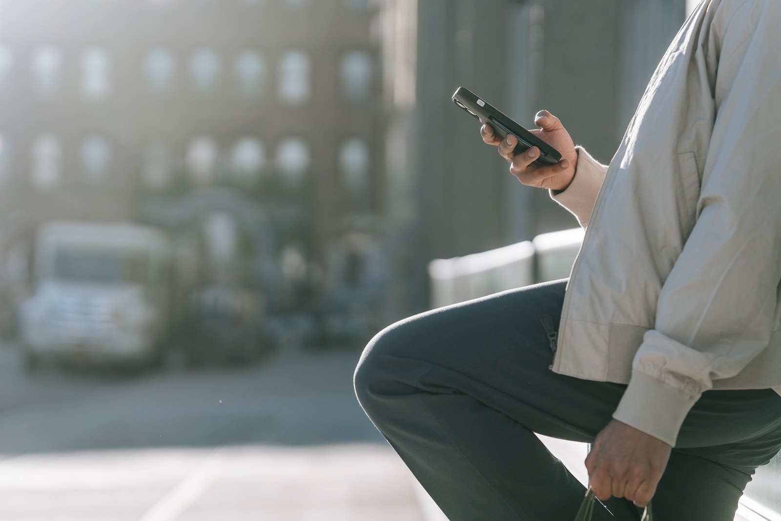 A person using a smartphone outdoors in bright sunlight, checking a website