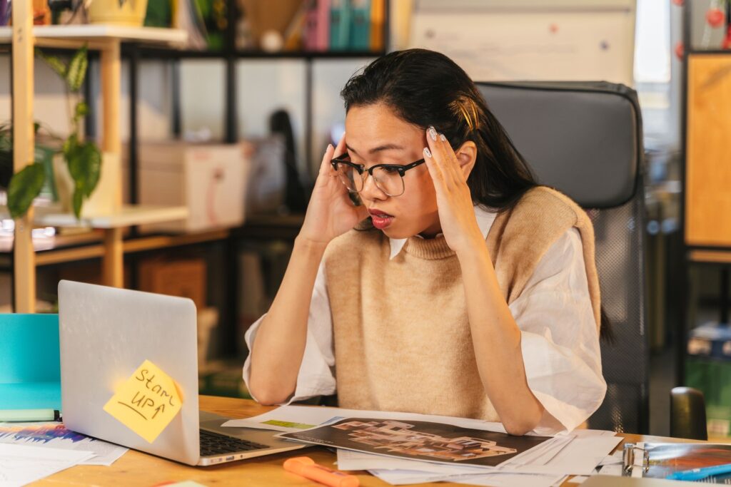 A nonprofit staff member looking frustrated while reviewing her laptop at a cluttered desk