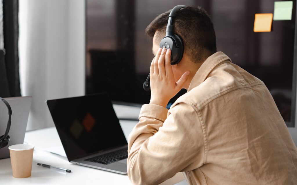 A person wearing noise canceling headphones, focused at a laptop with no other tabs open