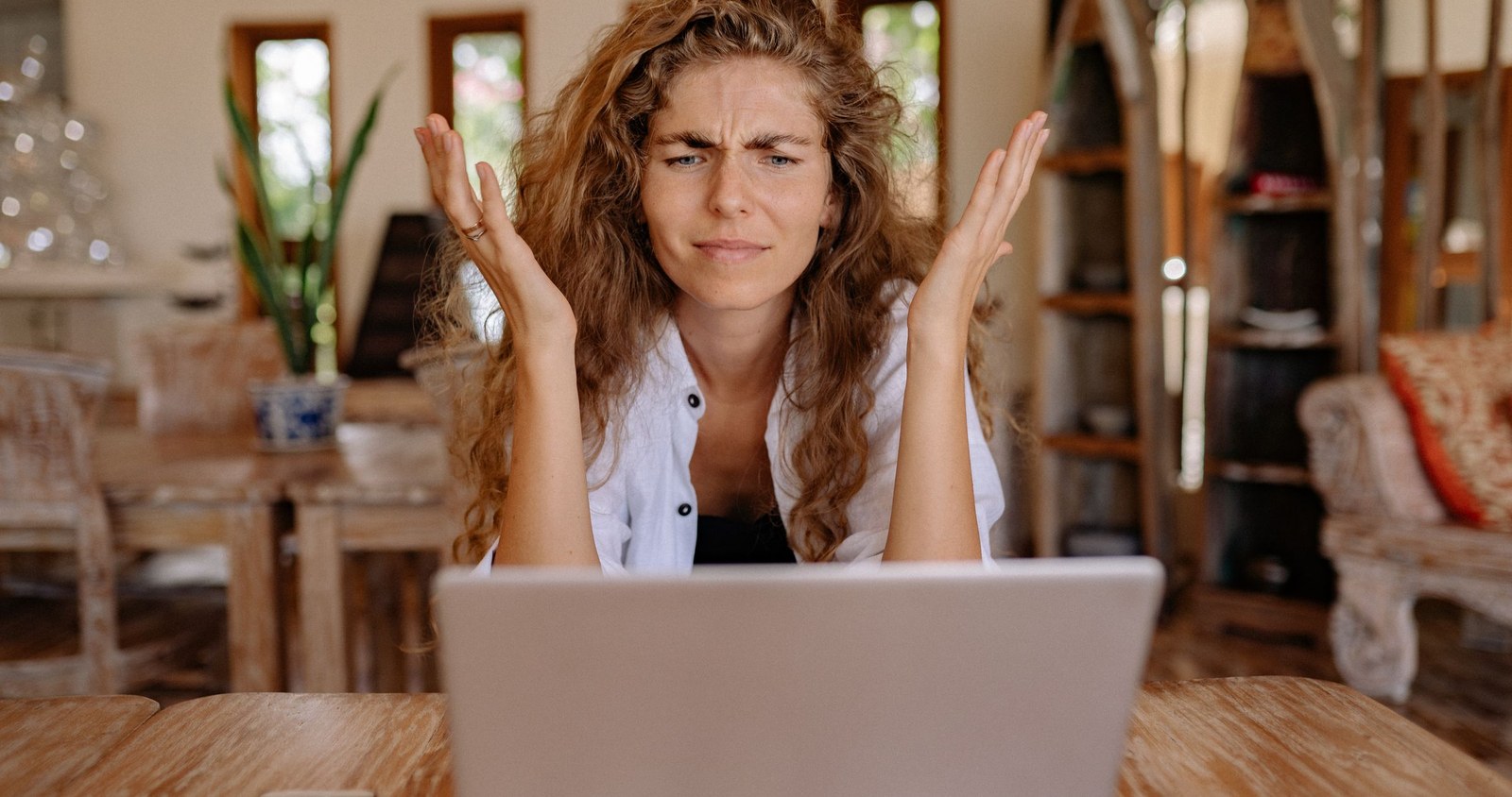 A frustrated business owner throwing up her hands at her laptop screen