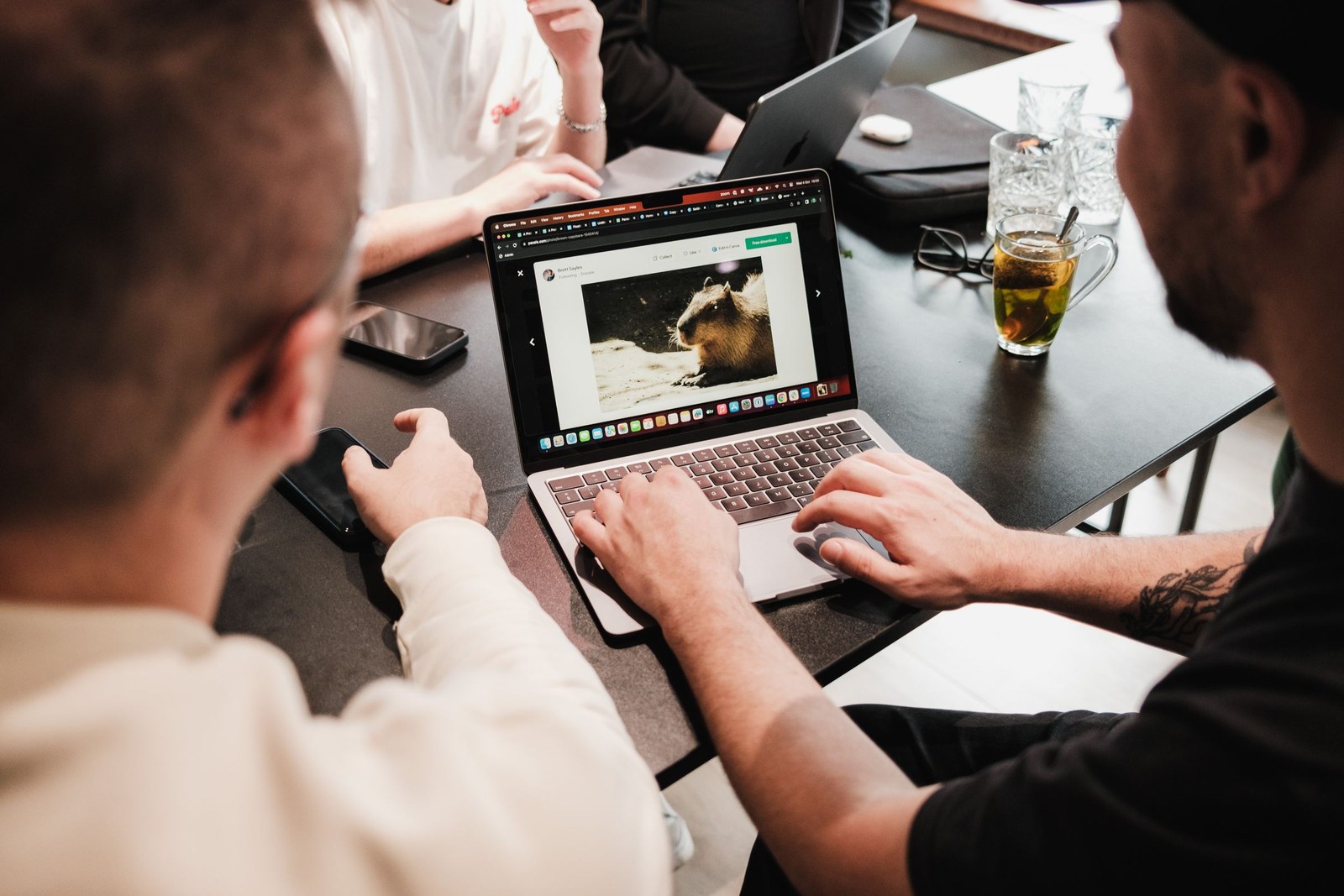 2 people sitting at a table reviewing a web page on a laptop together